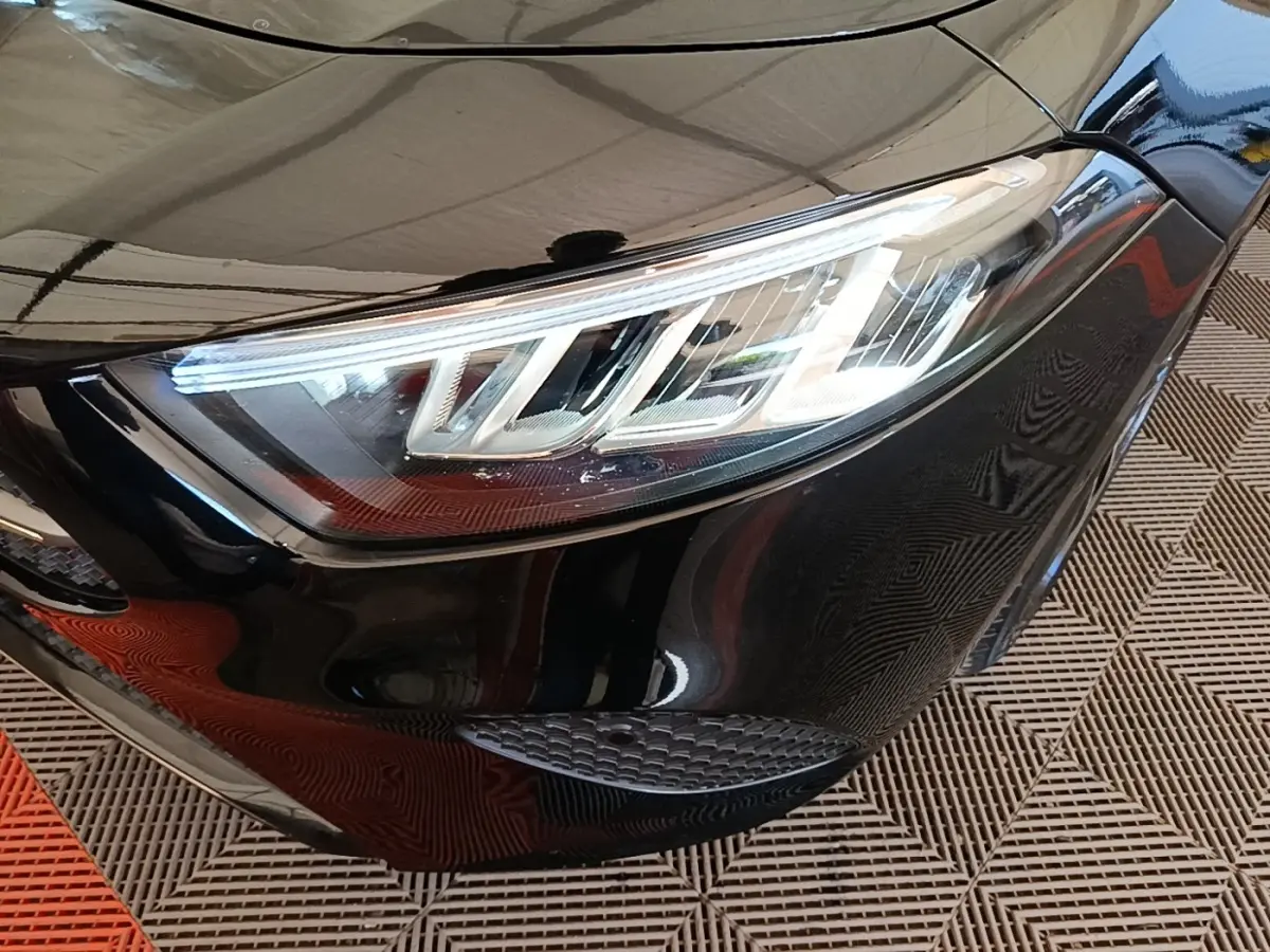 Gros plan sur le phare avant droit LED d'une Mercedes Classe A 250 e Business Line noire, vue en léger angle.