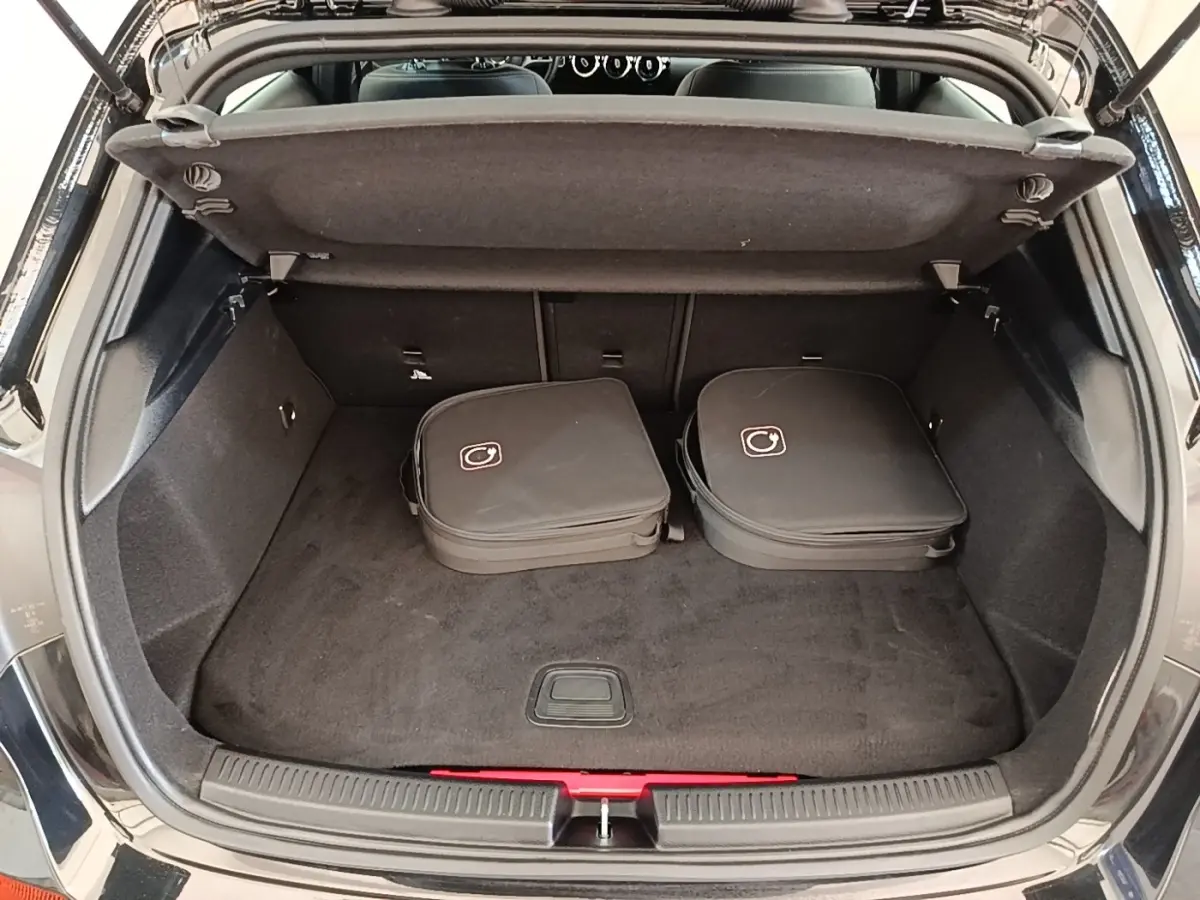 Coffre ouvert d'une Mercedes Classe A 250 e Business Line noir, avec deux sacs de charge posés à l'intérieur.