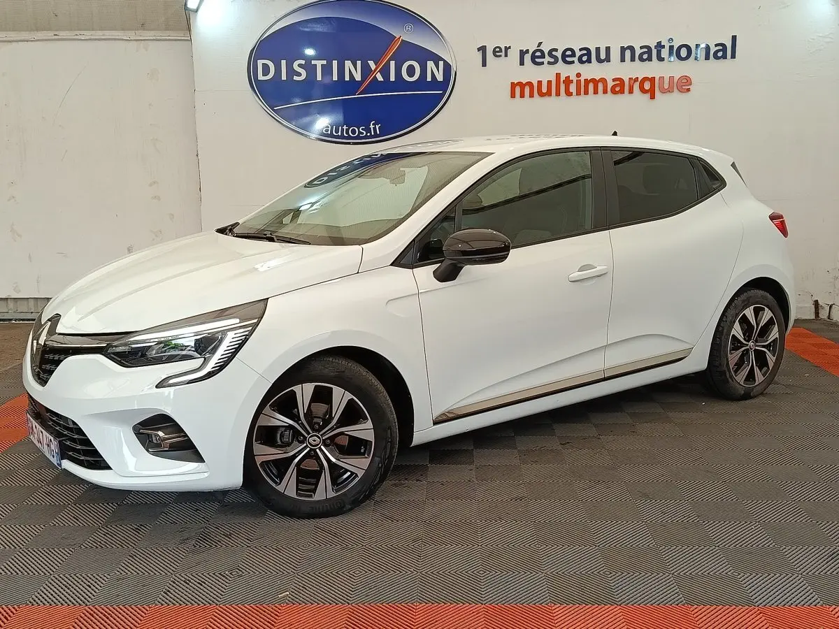 Renault Clio Evolution TCe 100 GPL blanche vue de profil droit en intérieur avec jantes alliage et rétroviseurs noirs.