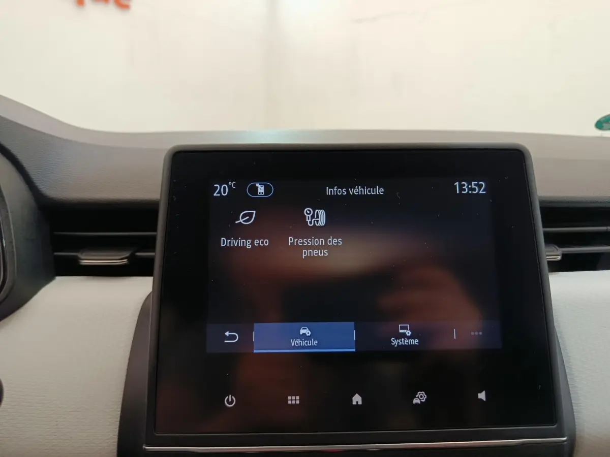 Écran tactile central affichant les infos véhicule dans l’habitacle d’une Renault Clio blanche, vue de face.