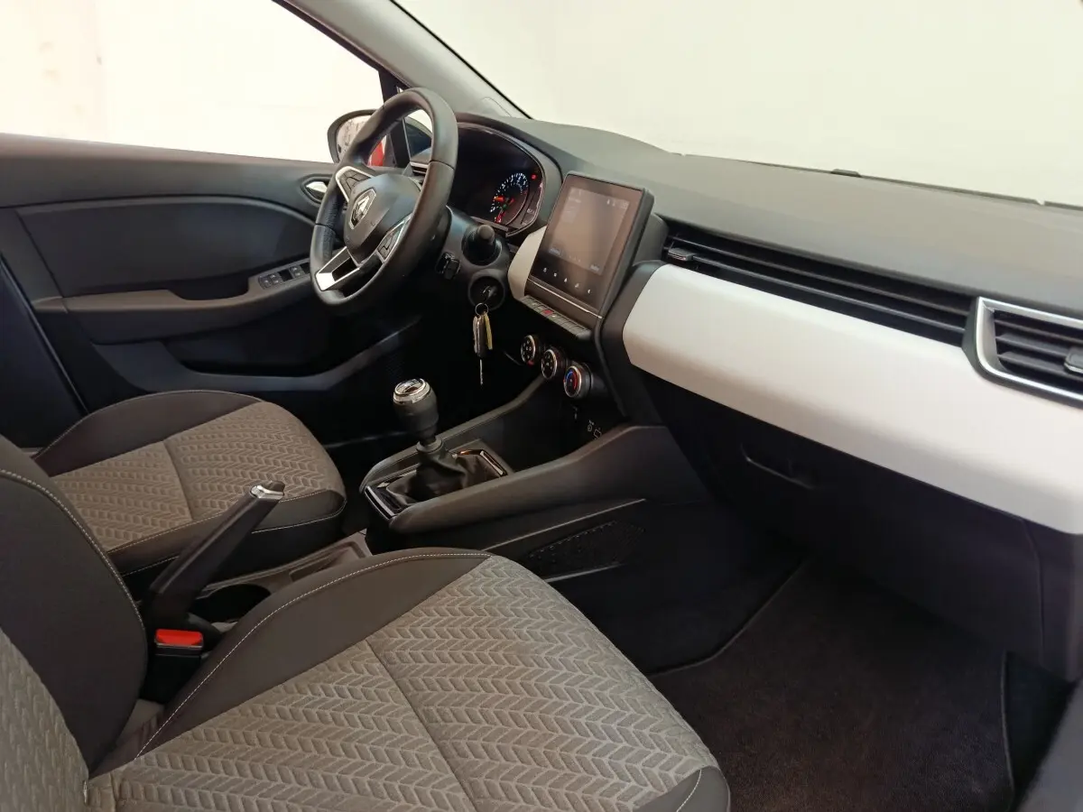 Intérieur avant droit de la Renault Clio Evolution TCe 100 GPL 2023, avec tableau de bord noir et blanc et volant multifonctions.