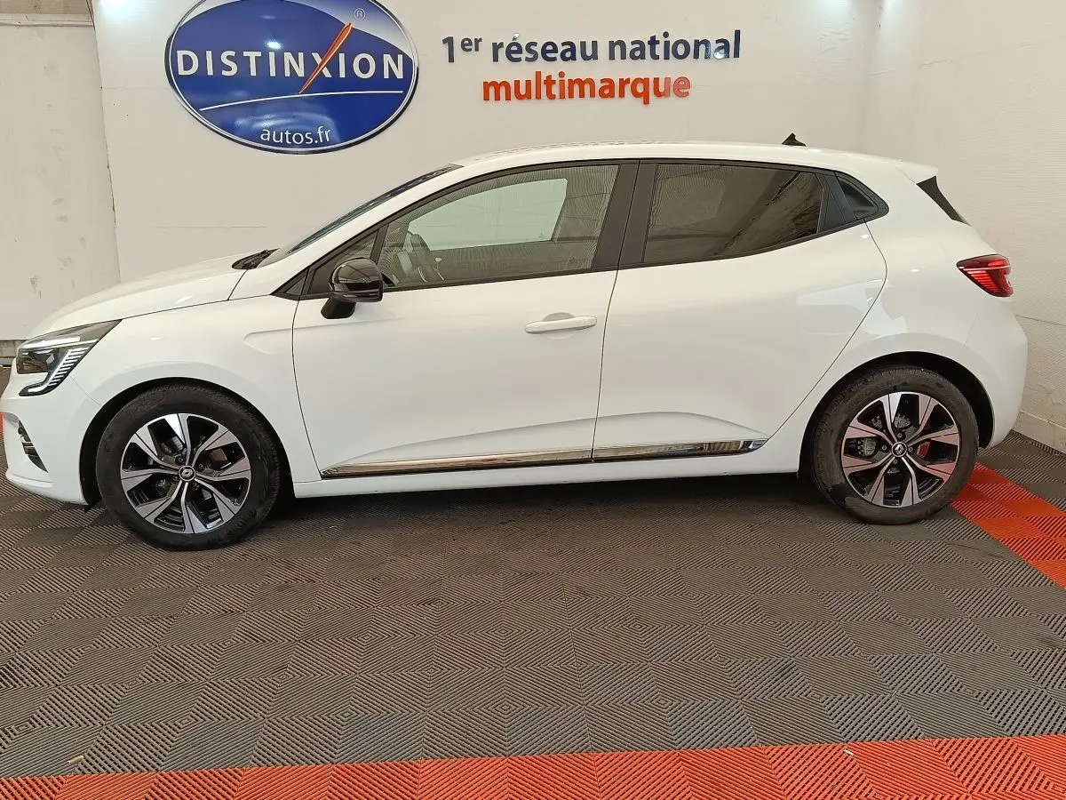 Profil droit d'une Renault Clio blanche Evolution TCe 100 GPL 2023 avec jantes alliage et rétroviseurs noirs.
