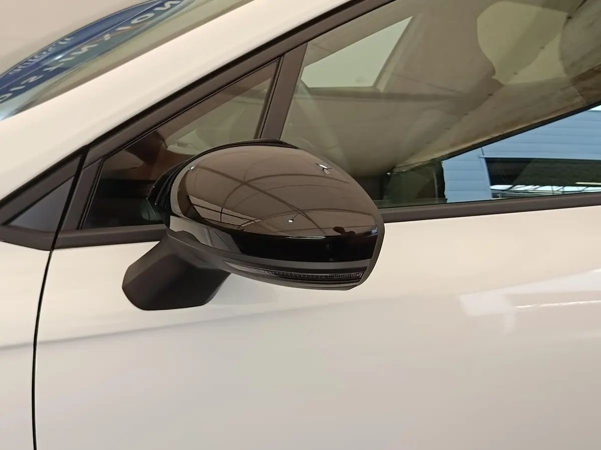 Rétroviseur droit noir brillant sur Renault Clio blanche vue de profil côté conducteur.
