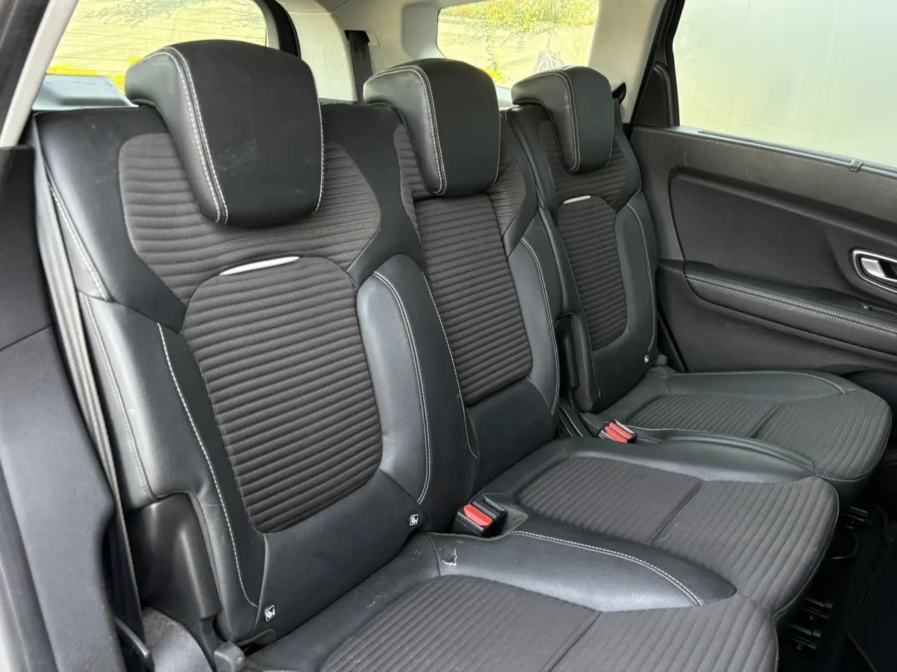 Vue latérale droite sur les sièges arrière en cuir noir avec surpiqûres blanches du Renault Grand Scenic IV 2021.