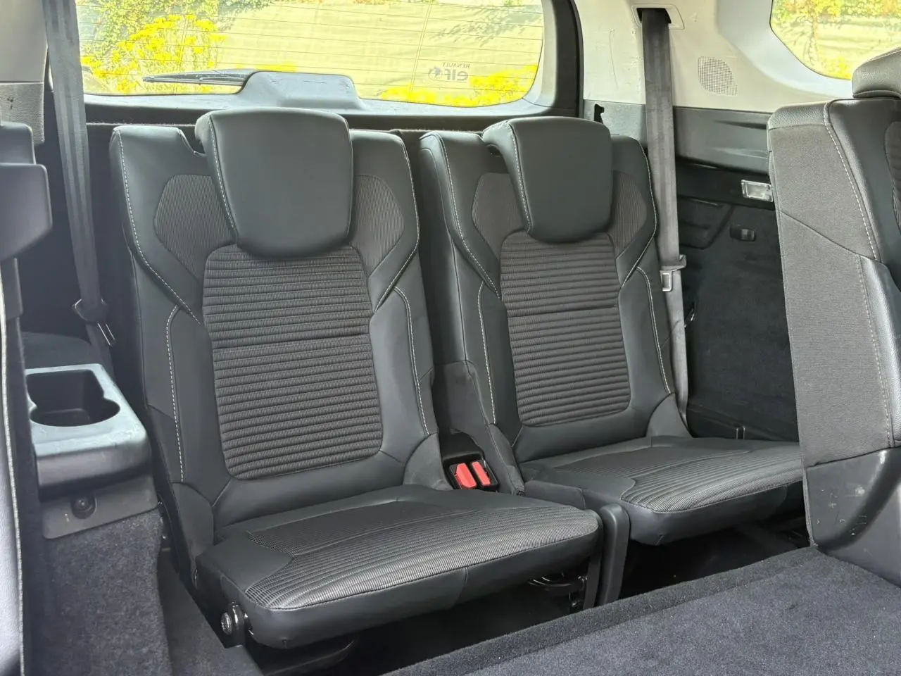 Vue intérieure arrière du Renault Grand Scenic IV 7 places, montrant les sièges en cuir noir avec surpiqûres blanches.