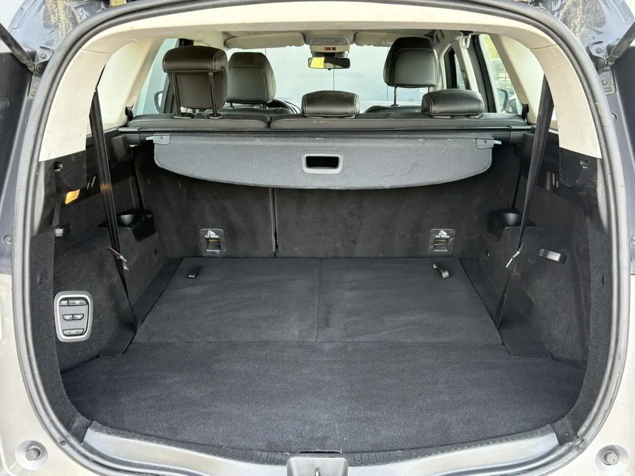 Coffre ouvert vu de l'arrière du Renault Grand Scenic gris Cassiopée, montrant l'espace et la banquette rabattue.