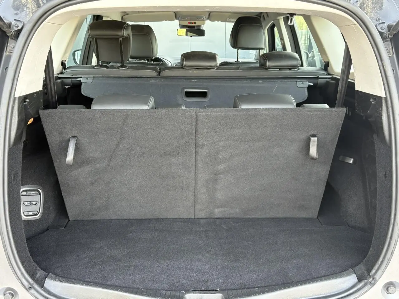 Coffre ouvert vu de l'arrière du Renault Grand Scenic gris Cassiopée, montrant la troisième rangée de sièges relevée.