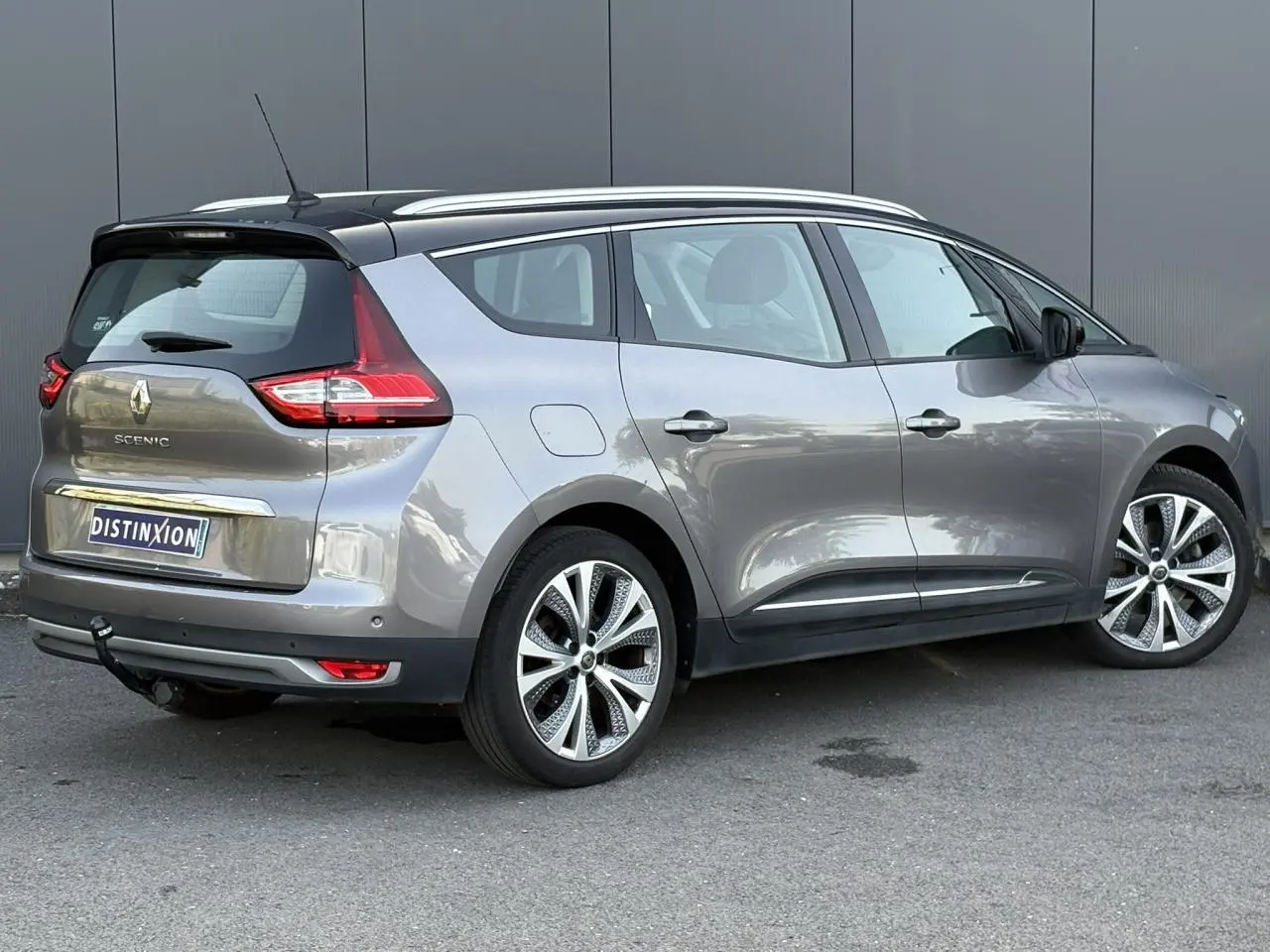Vue 3/4 arrière droit du Renault Grand Scénic IV gris Cassiopée avec jantes alliage 20 pouces et attelage visible.