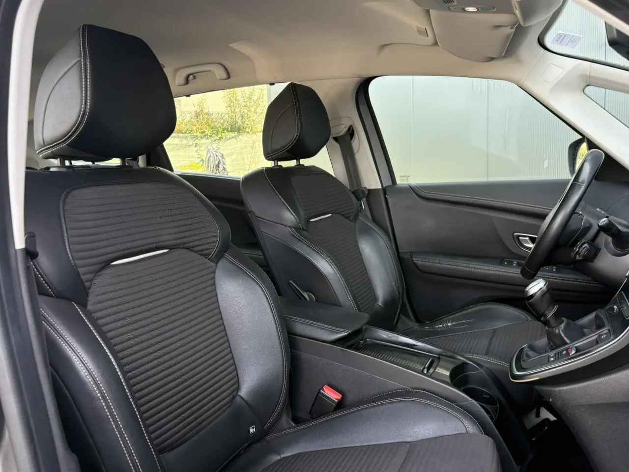 Vue intérieure côté avant droit du Renault Grand Scenic 2021, sièges noirs avec surpiqûres blanches et levier de vitesse manuel.