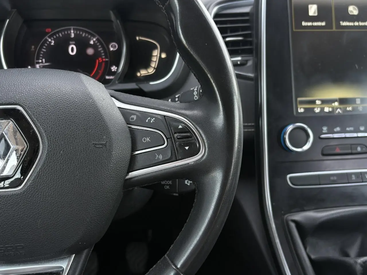 Vue rapprochée du volant cuir noir de la Renault Grand Scenic IV avec commandes intégrées et tableau de bord numérique.