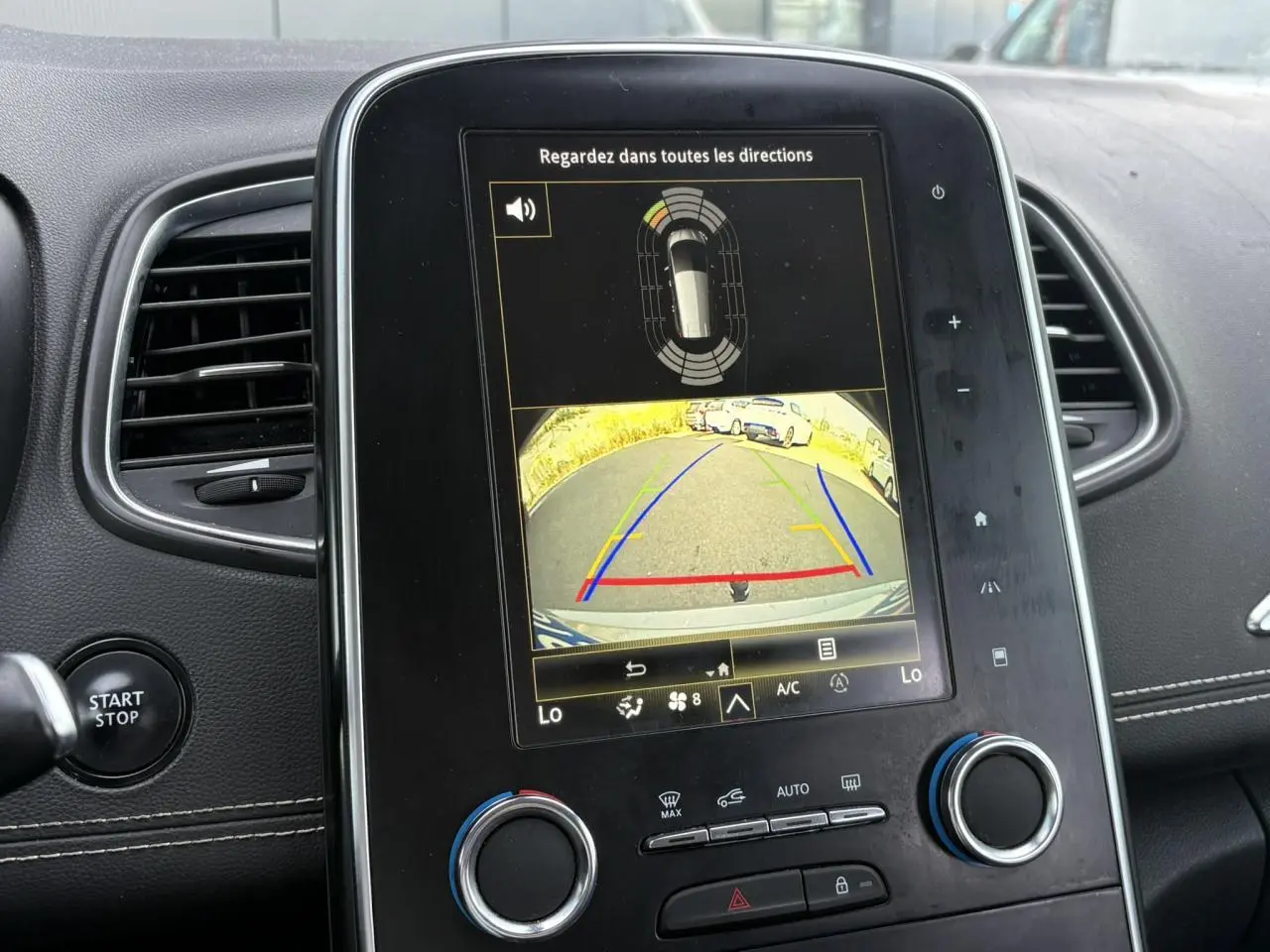 Vue rapprochée de l’écran tactile central du Renault Grand Scenic IV affichant la caméra de recul et l’aide au stationnement.