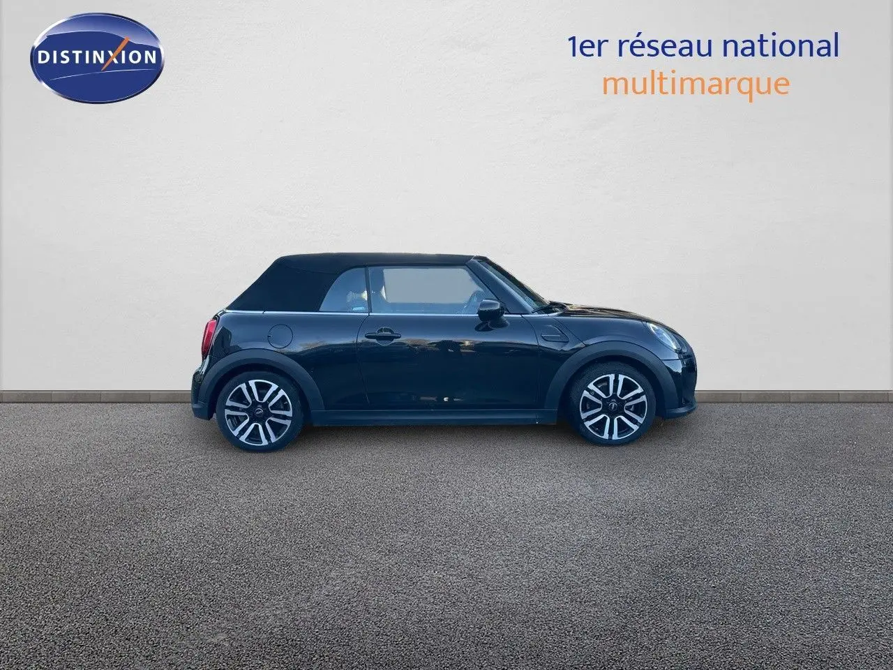 Profil côté gauche d'une MINI Cabriolet F57 noire Midnight Metal avec capote fermée, jantes bi-ton et deux portes visibles.