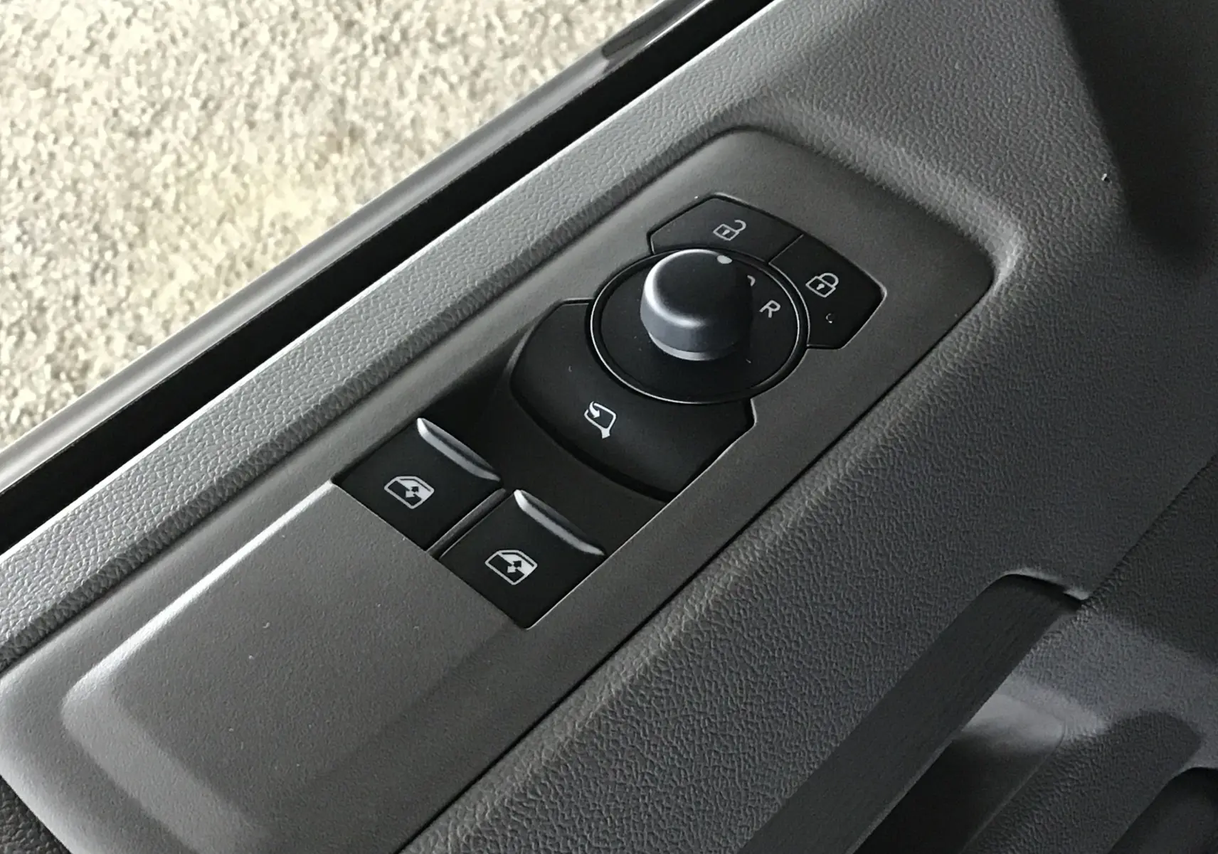 Panneau de commandes des vitres et rétroviseurs côté conducteur du Volkswagen Transporter T7 gris anthracite, intérieur.