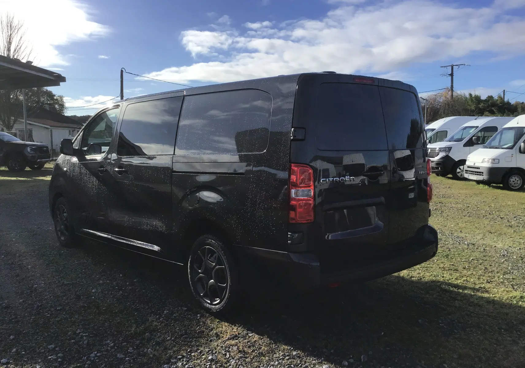 Vue 3/4 arrière droite d'un Citroën Jumpy cabine approfondie gris titane avec vitres teintées et jantes noires.