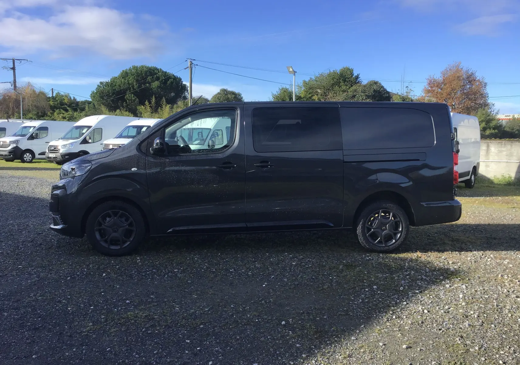 Vue latérale droite d'un Citroën Jumpy cabine approfondie gris titane, avec jantes noires et carrosserie lisse sans fenêtres arrière.