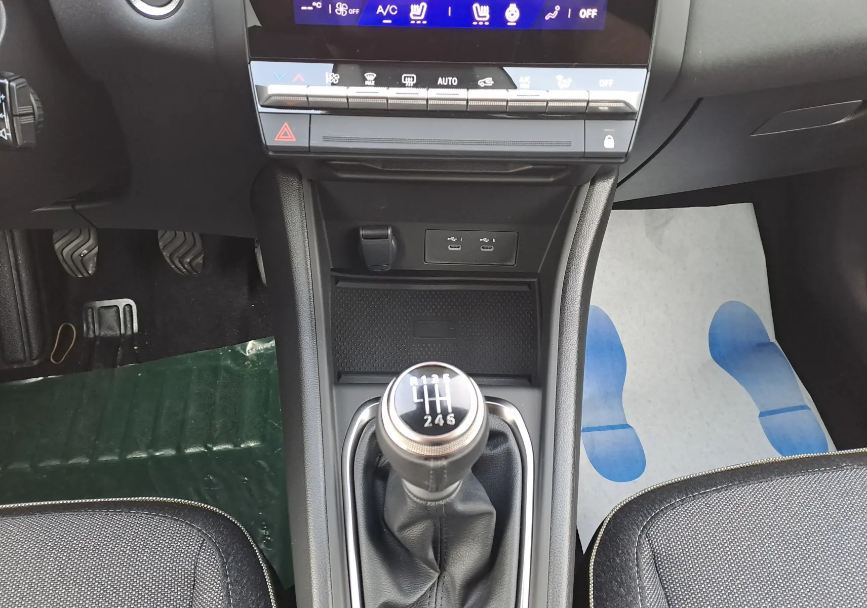 Vue intérieure centrée sur le levier de vitesses manuel de la Renault Symbioz gris Cassiopée avec console et commandes climatisation.