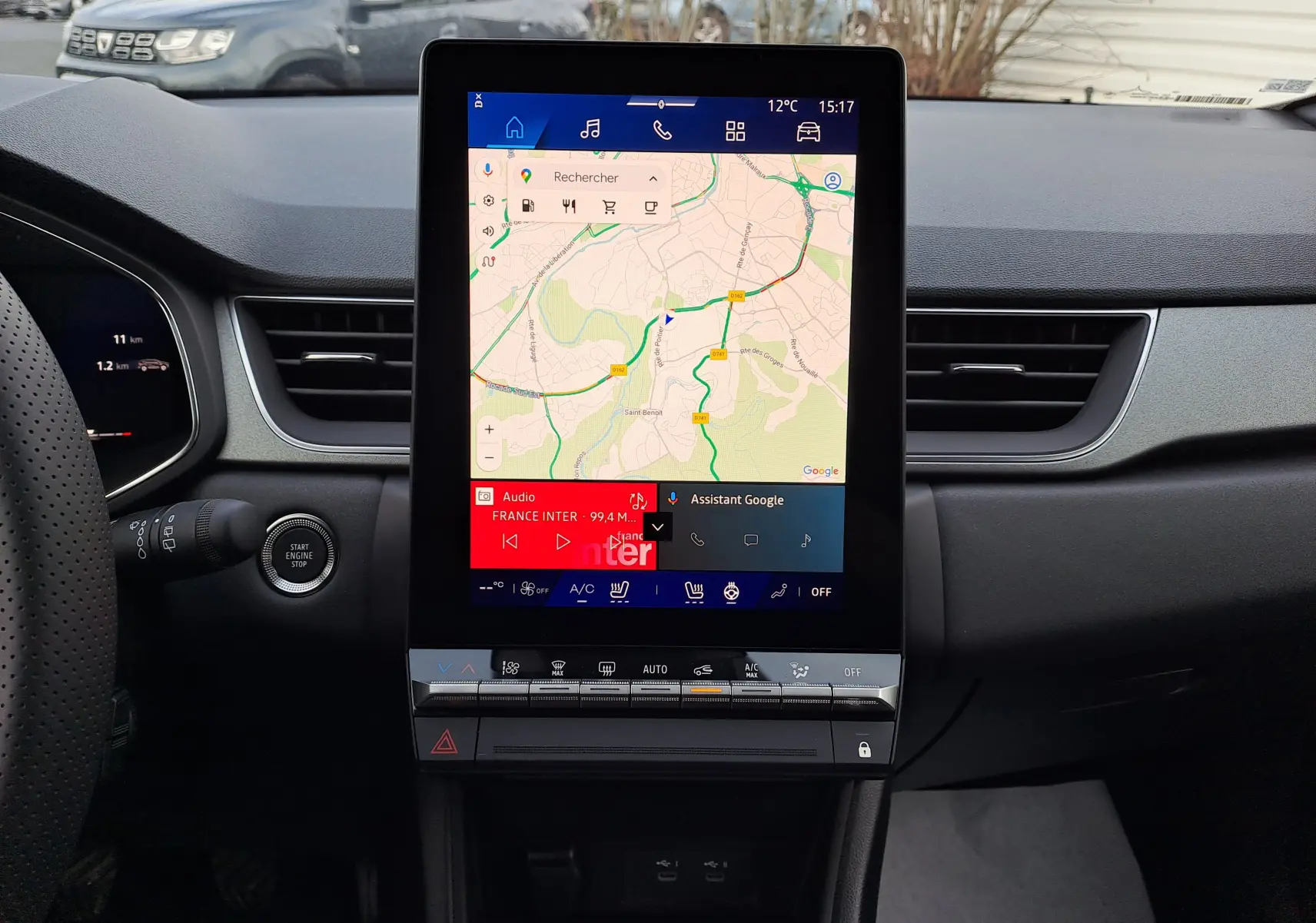 Vue intérieure centrée sur l'écran tactile vertical du tableau de bord du Renault Symbioz gris Cassiopée, avec commandes climatisation en dessous.