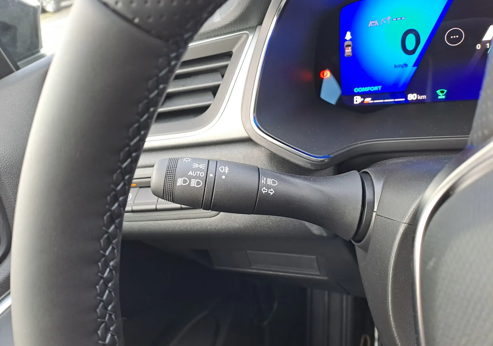 Gros plan sur la manette des feux et clignotants à gauche du volant dans l’habitacle noir du Renault Symbioz gris Cassiopée.