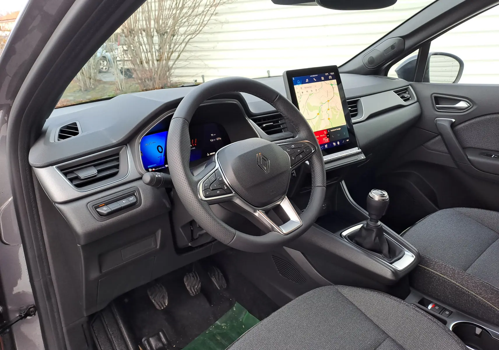 Vue intérieure côté conducteur de la Renault Symbioz gris Cassiopée, volant multifonction et écran tactile vertical.
