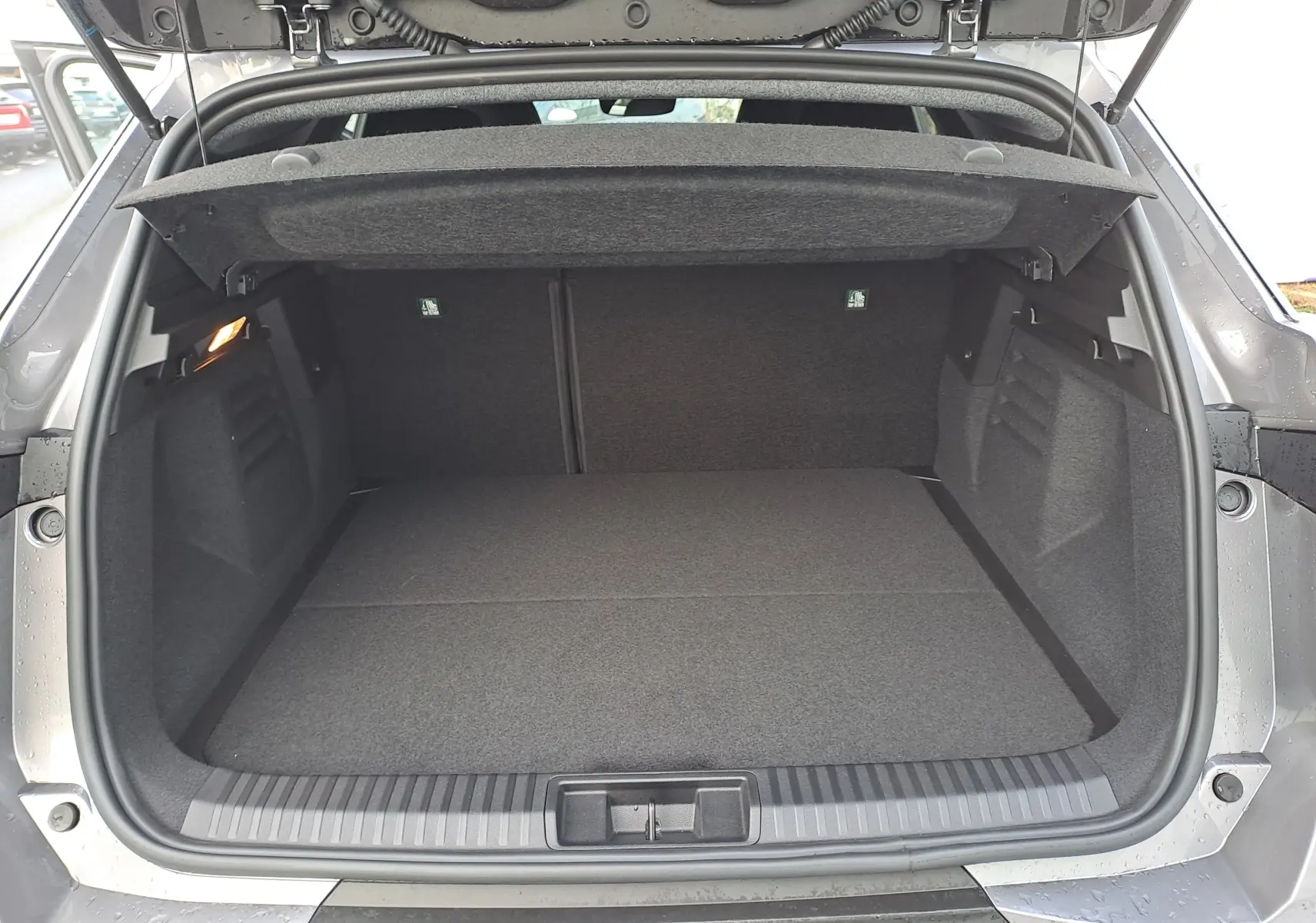 Coffre ouvert vu de l'arrière d'une Renault Symbioz gris Cassiopée, montrant un espace de chargement propre et spacieux.