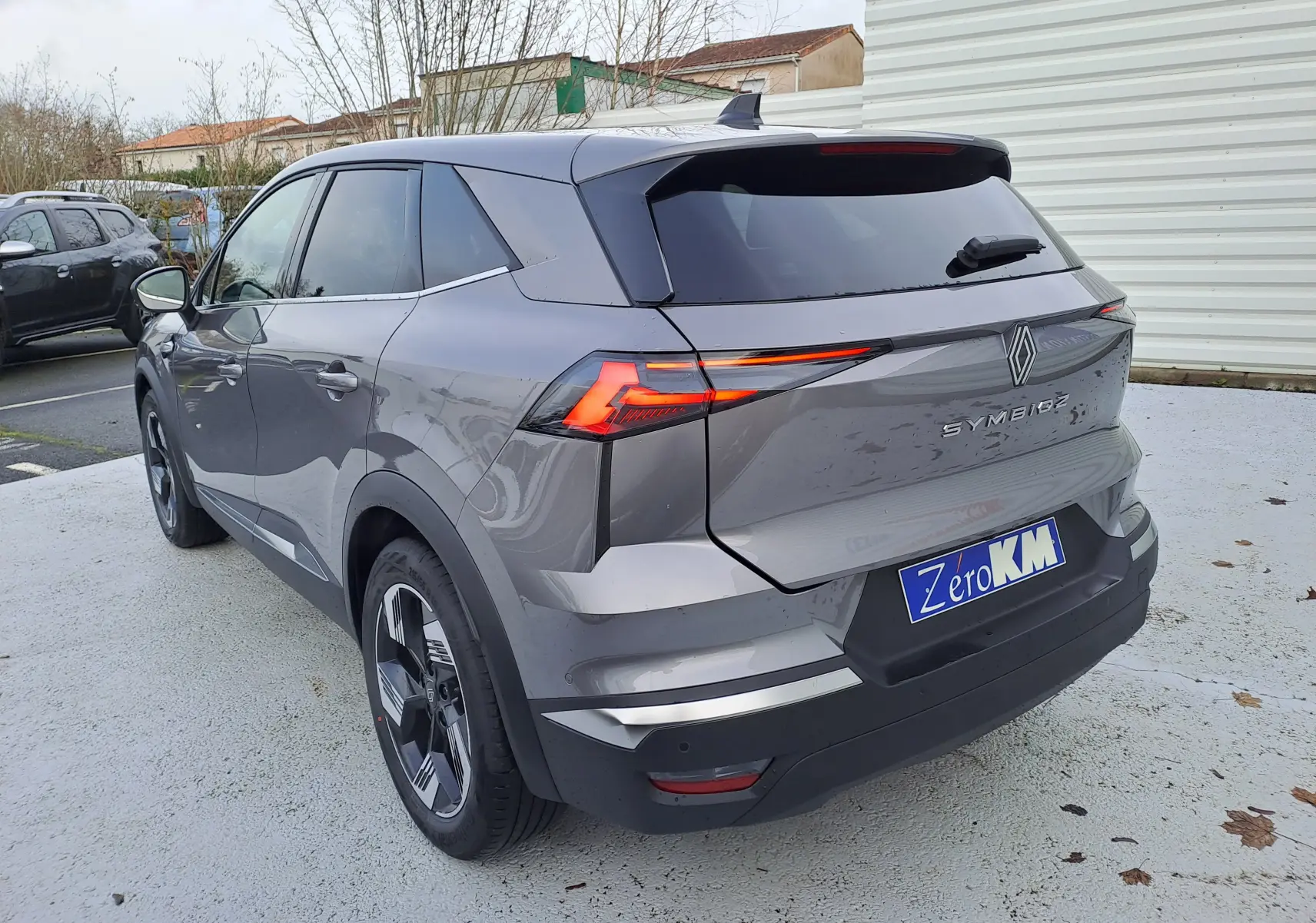 Vue 3/4 arrière droite d'une Renault Symbioz gris Cassiopée avec feux arrière LED et toit noir brillant.