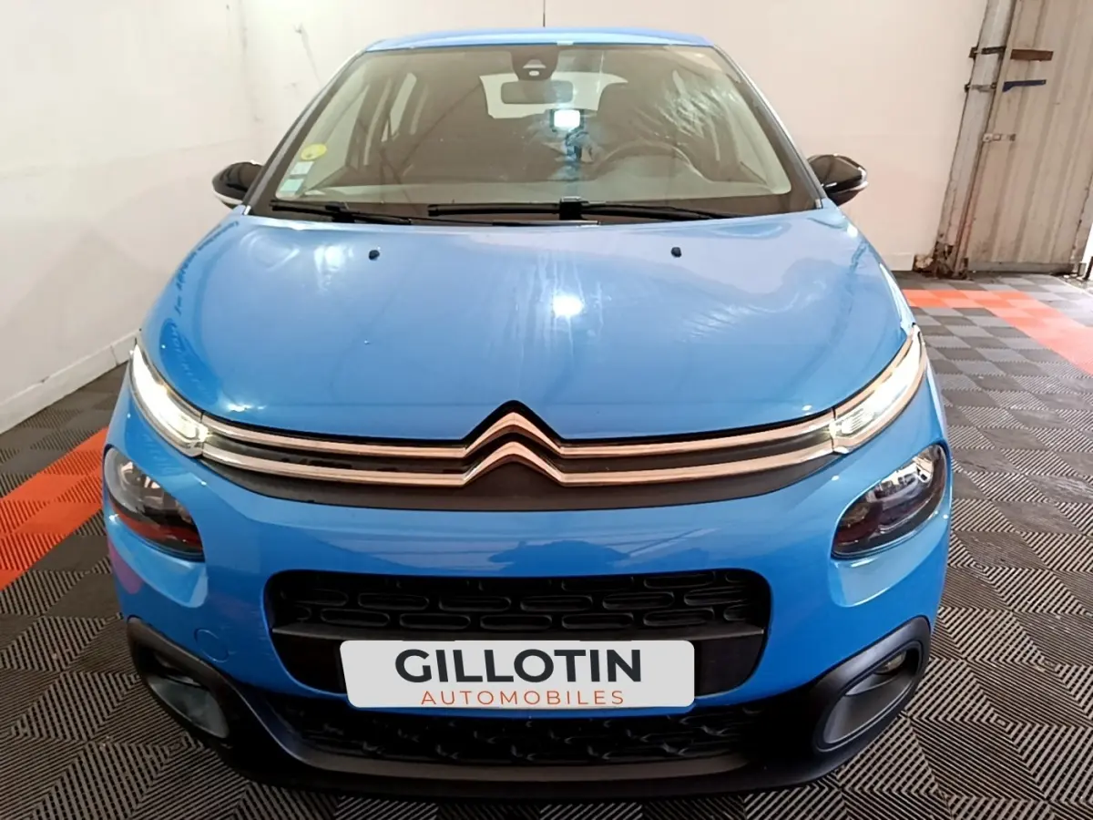 Vue frontale d'une Citroën C3 bleu vif avec feux LED et calandre noire dans un garage.