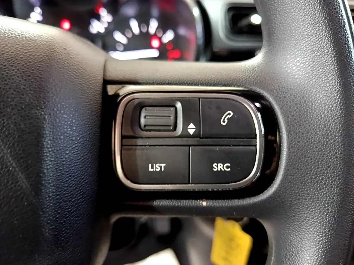 Gros plan sur les commandes audio au volant noir de la Citroën C3 BlueHDi 2017, boutons LIST et SRC visibles.
