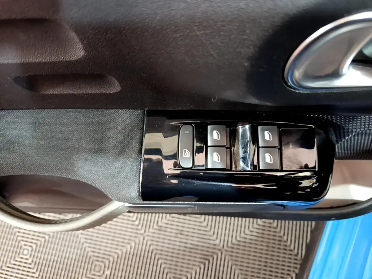 Commande des vitres électriques sur la porte côté conducteur d'une Citroën C3 bleu 2017, intérieur noir.