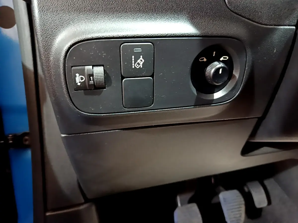 Vue rapprochée des commandes de réglage des phares et des rétroviseurs côté conducteur d'une Citroën C3 bleu 2017.
