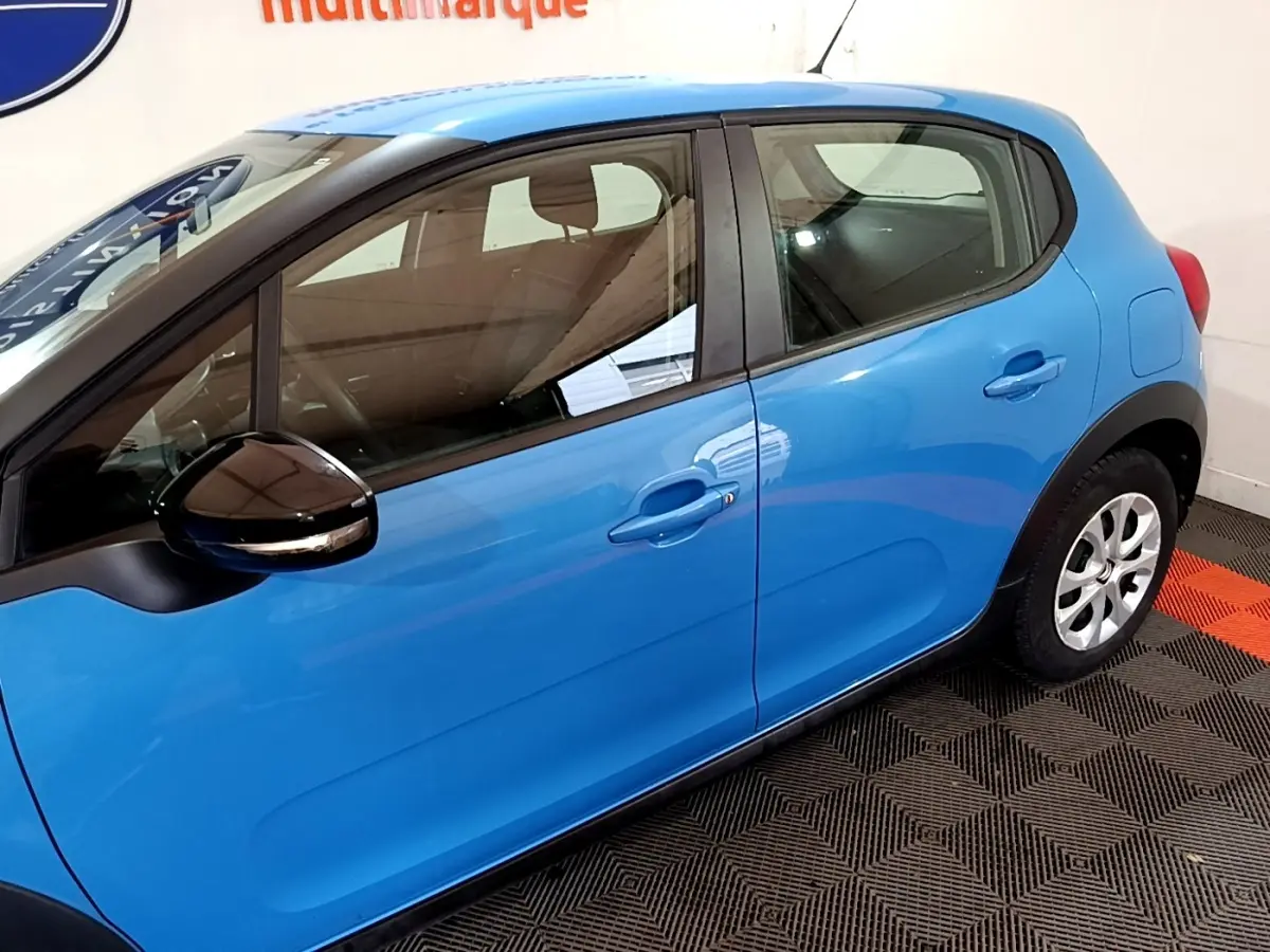 Vue latérale côté gauche d'une Citroën C3 bleu vif, avec rétroviseur noir et poignées de porte assorties.