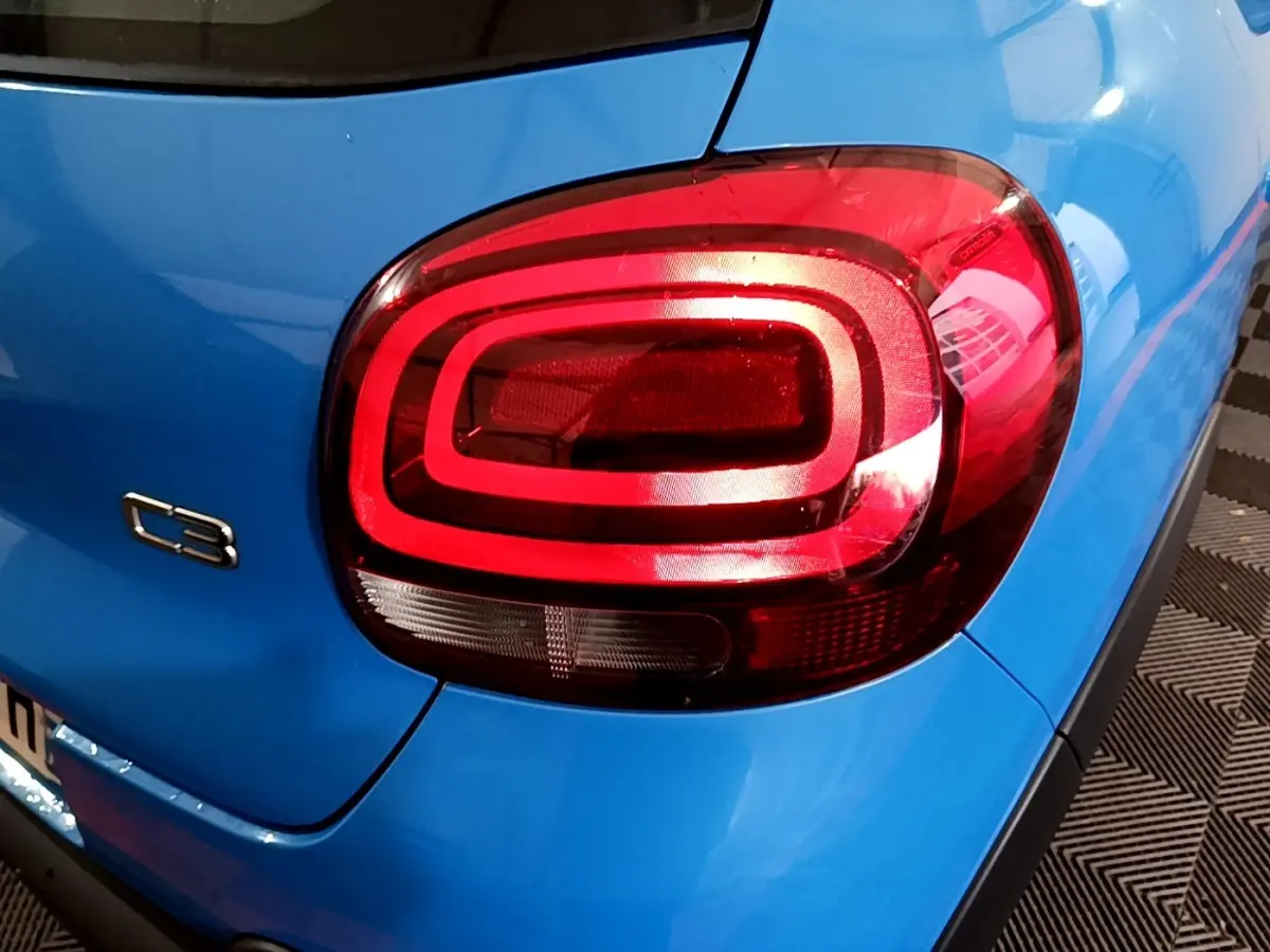 Gros plan sur le feu arrière droit rouge d'une Citroën C3 bleue 2017, avec logo C3 visible sur la carrosserie.