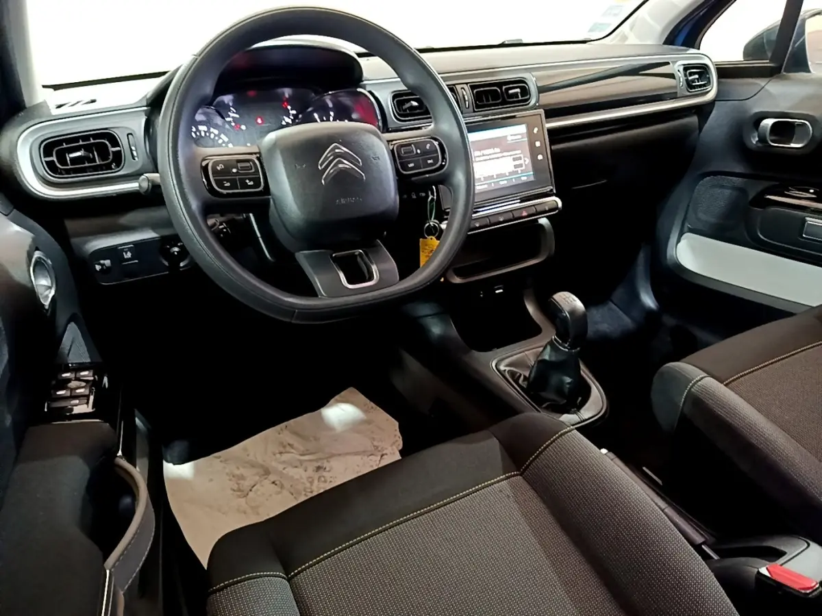 Intérieur avant de la Citroën C3 2017 avec tableau de bord noir, volant multifonctions et boîte manuelle visible côté conducteur.