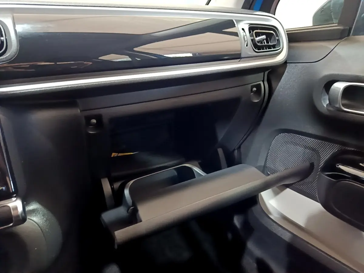 Intérieur de la Citroën C3 2017, vue du côté passager avec boîte à gants ouverte et tableau de bord noir brillant.