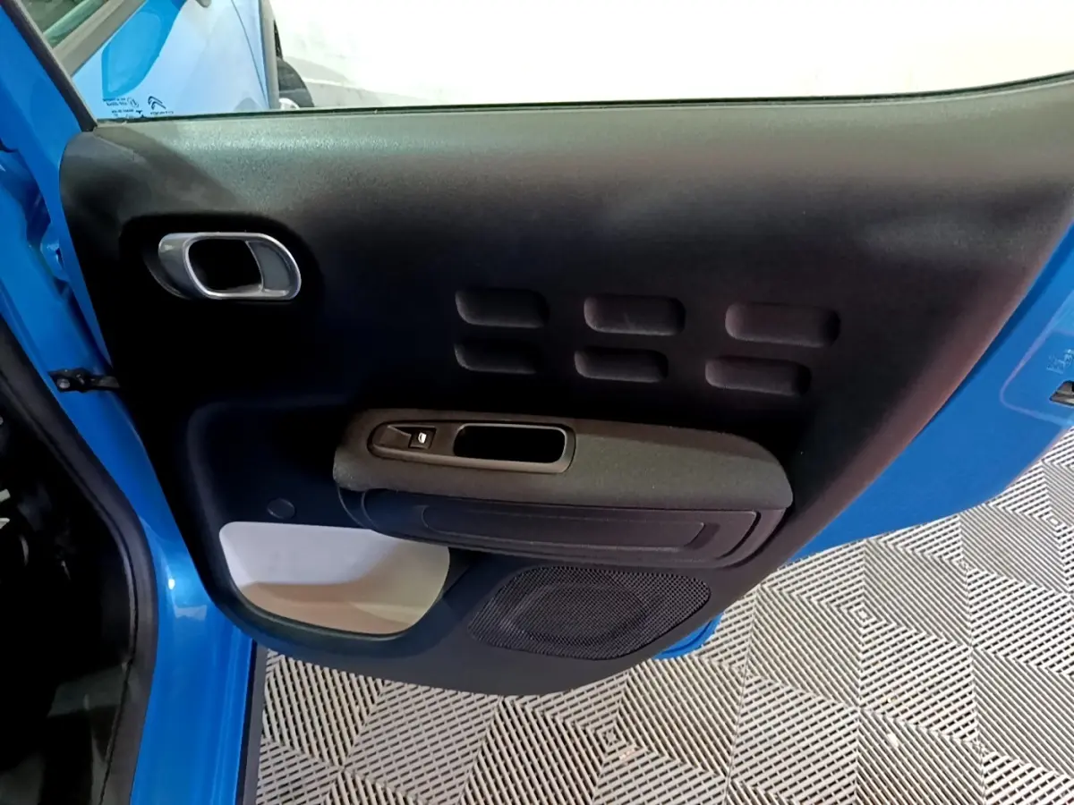 Vue rapprochée de la porte arrière gauche bleu vif de la Citroën C3 2017 avec panneau intérieur noir et poignée chromée.