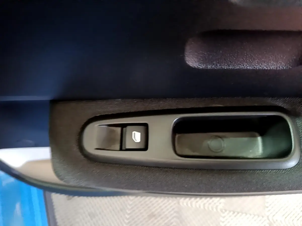 Gros plan sur la commande de lève-vitre côté conducteur d'une Citroën C3 bleu 2017.