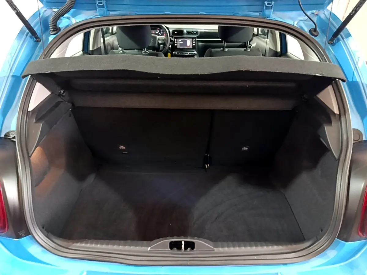 Coffre ouvert d'une Citroën C3 bleu, vue arrière montrant l'espace de chargement et l'intérieur avec écran tactile.
