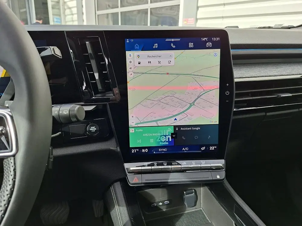 Vue intérieure centrée sur l'écran tactile vertical du tableau de bord du Renault Austral gris schiste, avec commandes climatisation visibles.