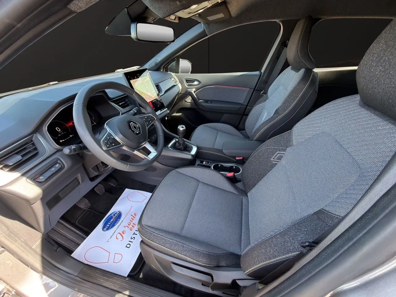 Vue intérieure côté conducteur du Renault Captur TCE 90 Techno 2024, sièges tissu gris Cassiopée avec volant multifonction.
