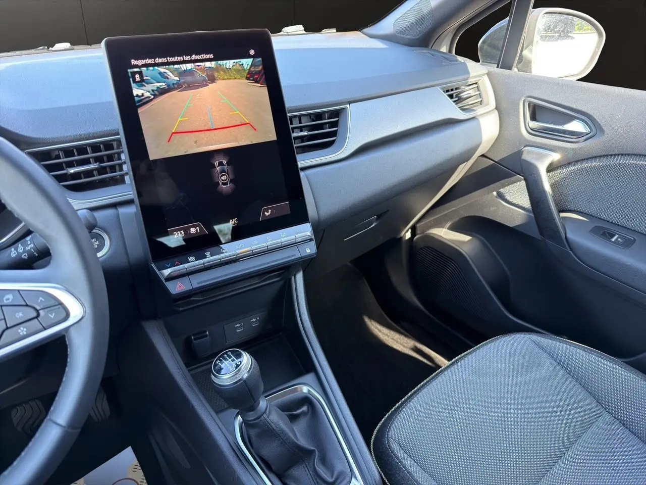 Vue intérieure côté passager du tableau de bord et console centrale du Renault Captur TCe 90 Techno 2024 avec écran tactile vertical et boîte manuelle.