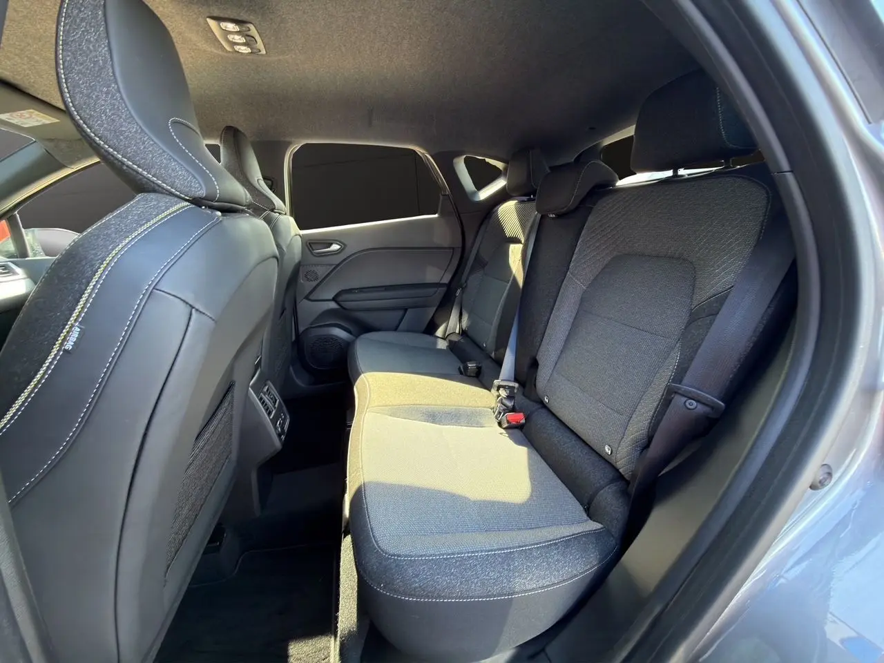 Vue intérieure arrière côté droit du Renault Captur 2024, sièges tissu noir avec surpiqûres blanches, portières gris cassiopée.