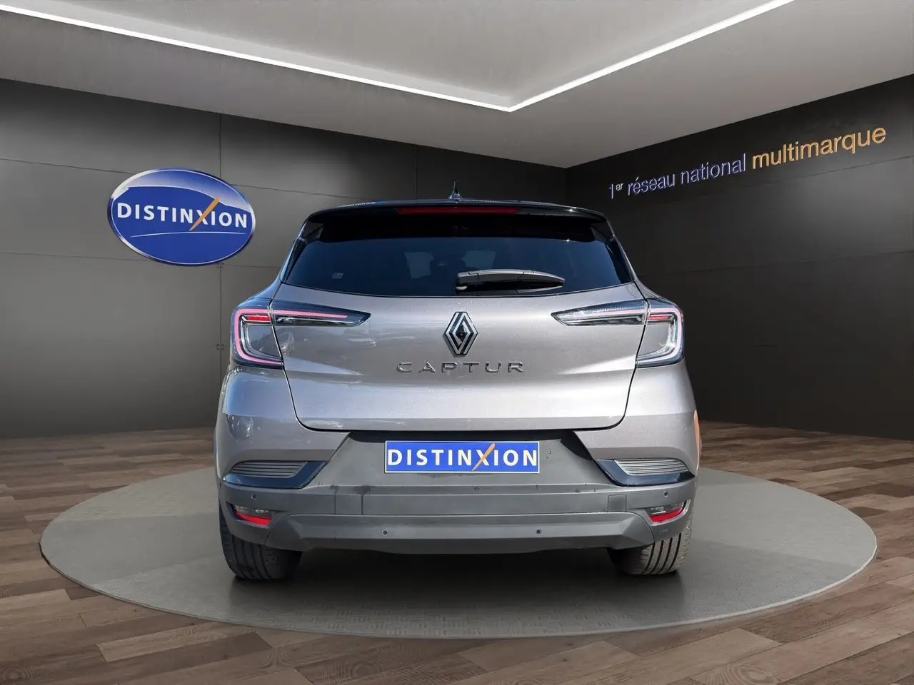 Vue arrière du Renault Captur TCE 90 Techno 2024 en gris Cassiopée avec toit noir, sur plateau en showroom.