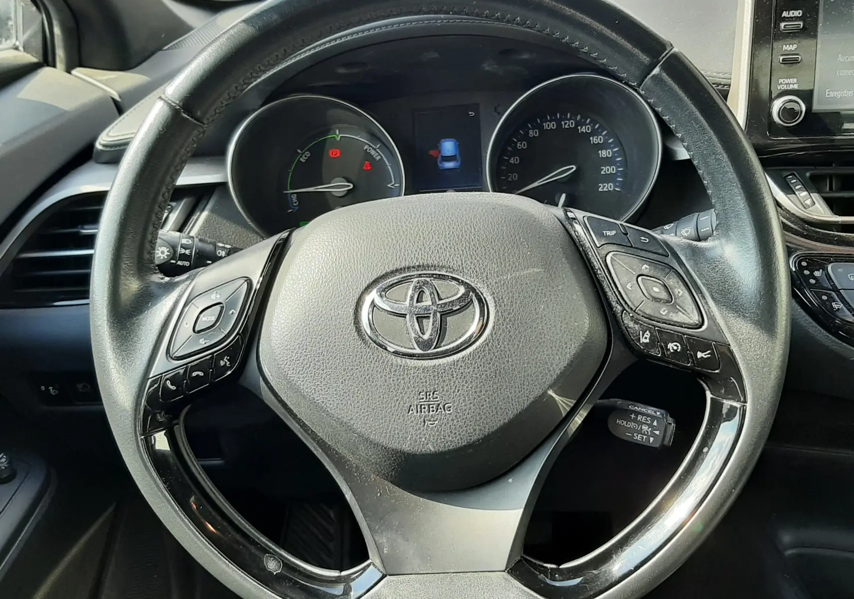 Vue rapprochée du volant noir du Toyota C-HR 1.8 Hybrid 2021, avec commandes intégrées et tableau de bord visible.