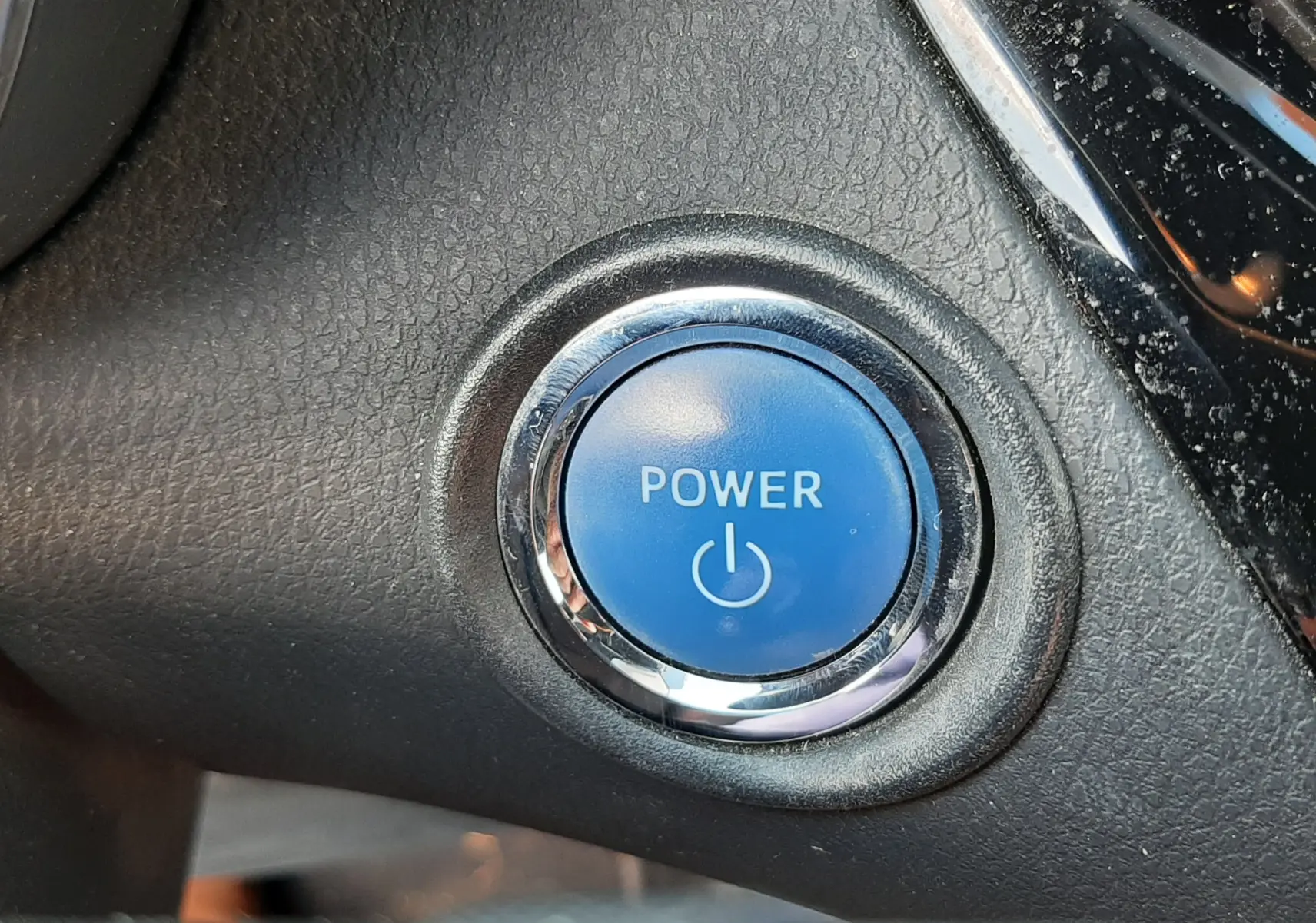 Bouton bleu Power en gros plan sur le tableau de bord intérieur du Toyota C-HR 1.8 Hybrid 2021 gris atlas metal.