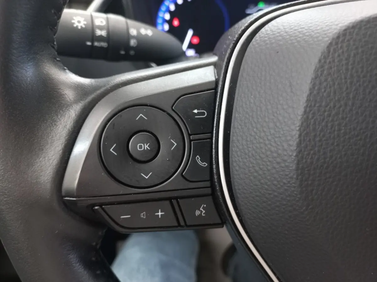 Gros plan sur les commandes multifonctions du volant cuir côté gauche de la Toyota Corolla hybride 2022.