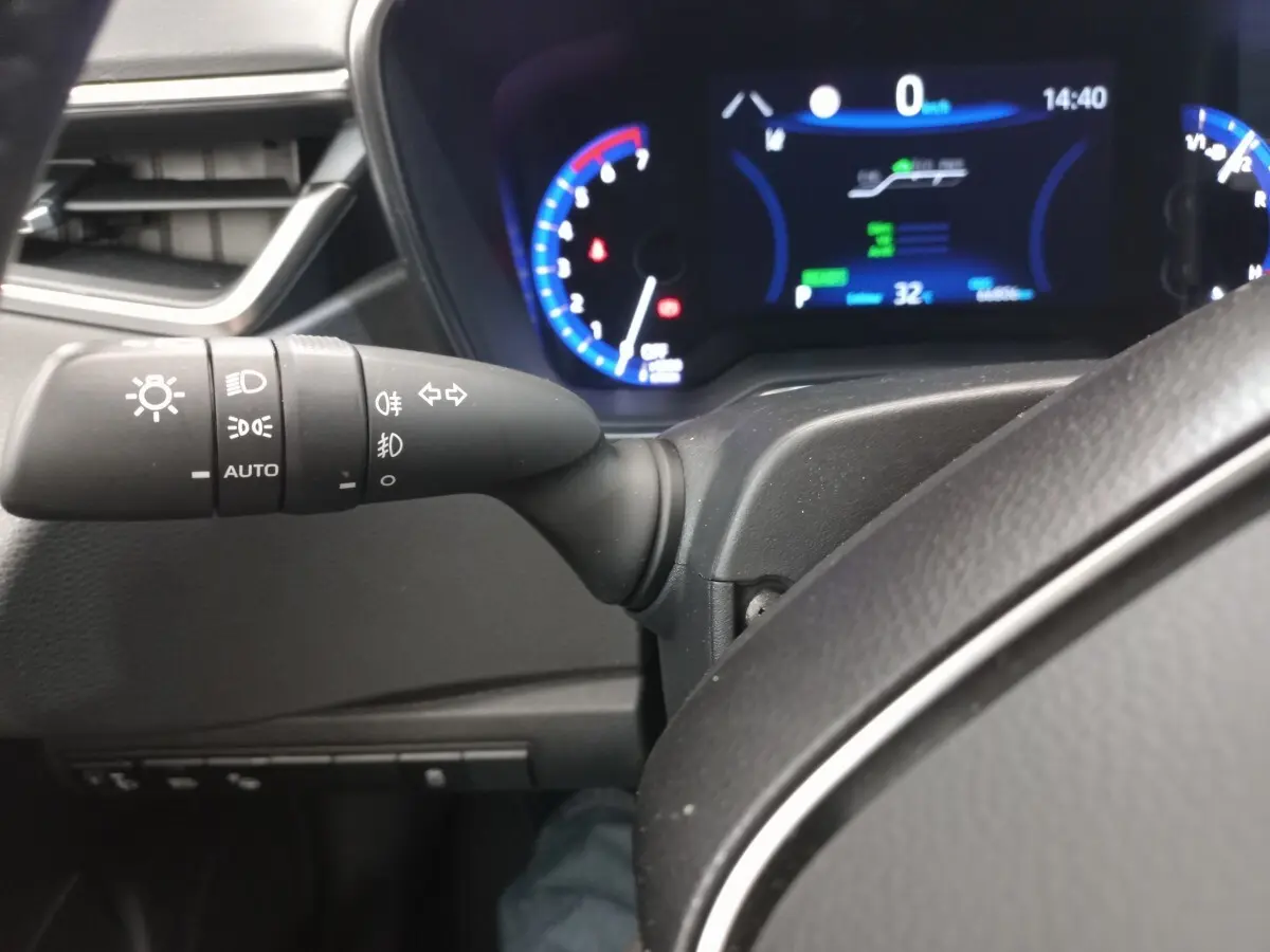Vue rapprochée du commodo gauche et du tableau de bord numérique bleu de la Toyota Corolla hybride 2022.