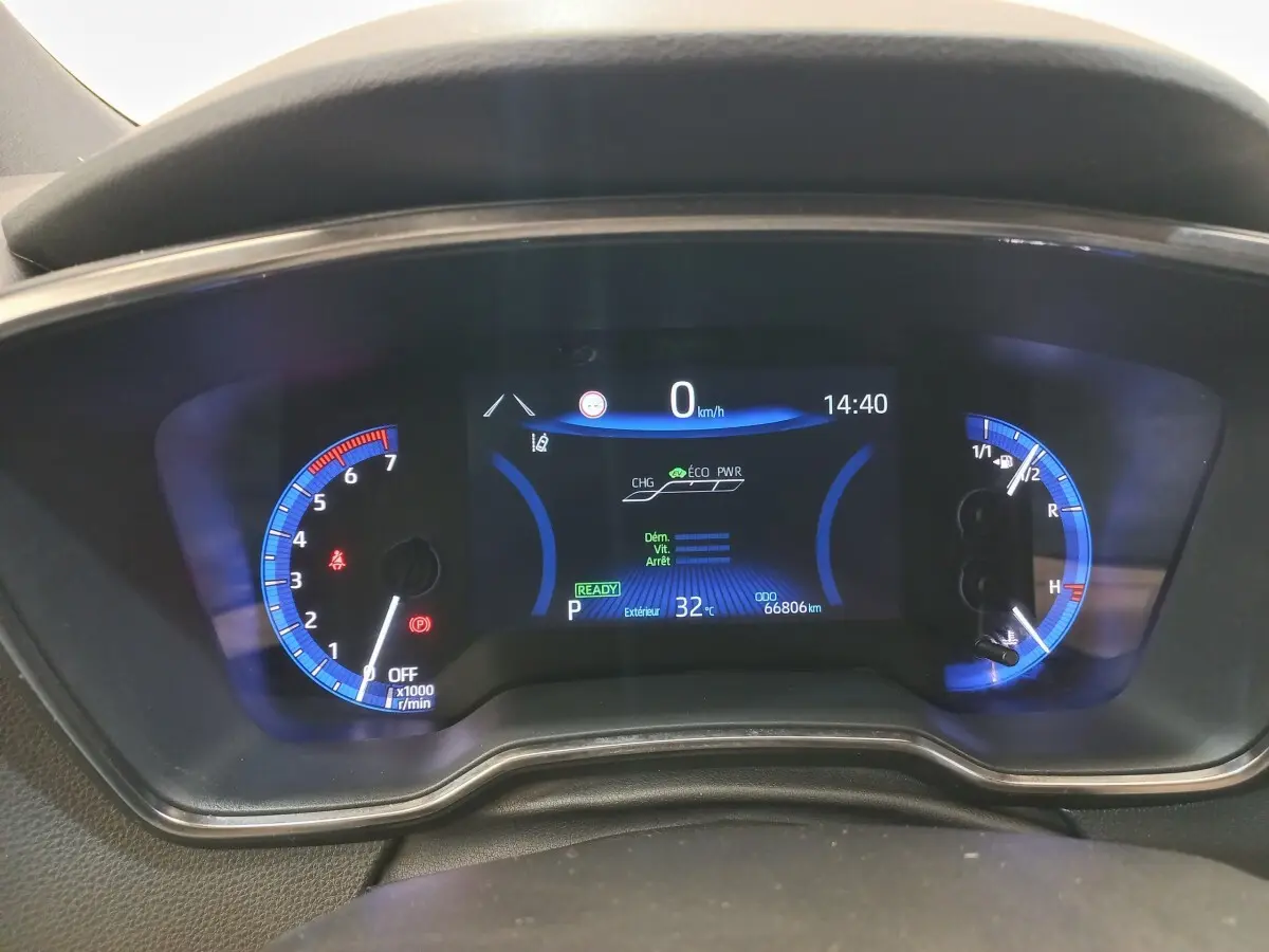 Tableau de bord numérique de la Toyota Corolla hybride 2022, affichage bleu avec compte-tours et jauge carburant.