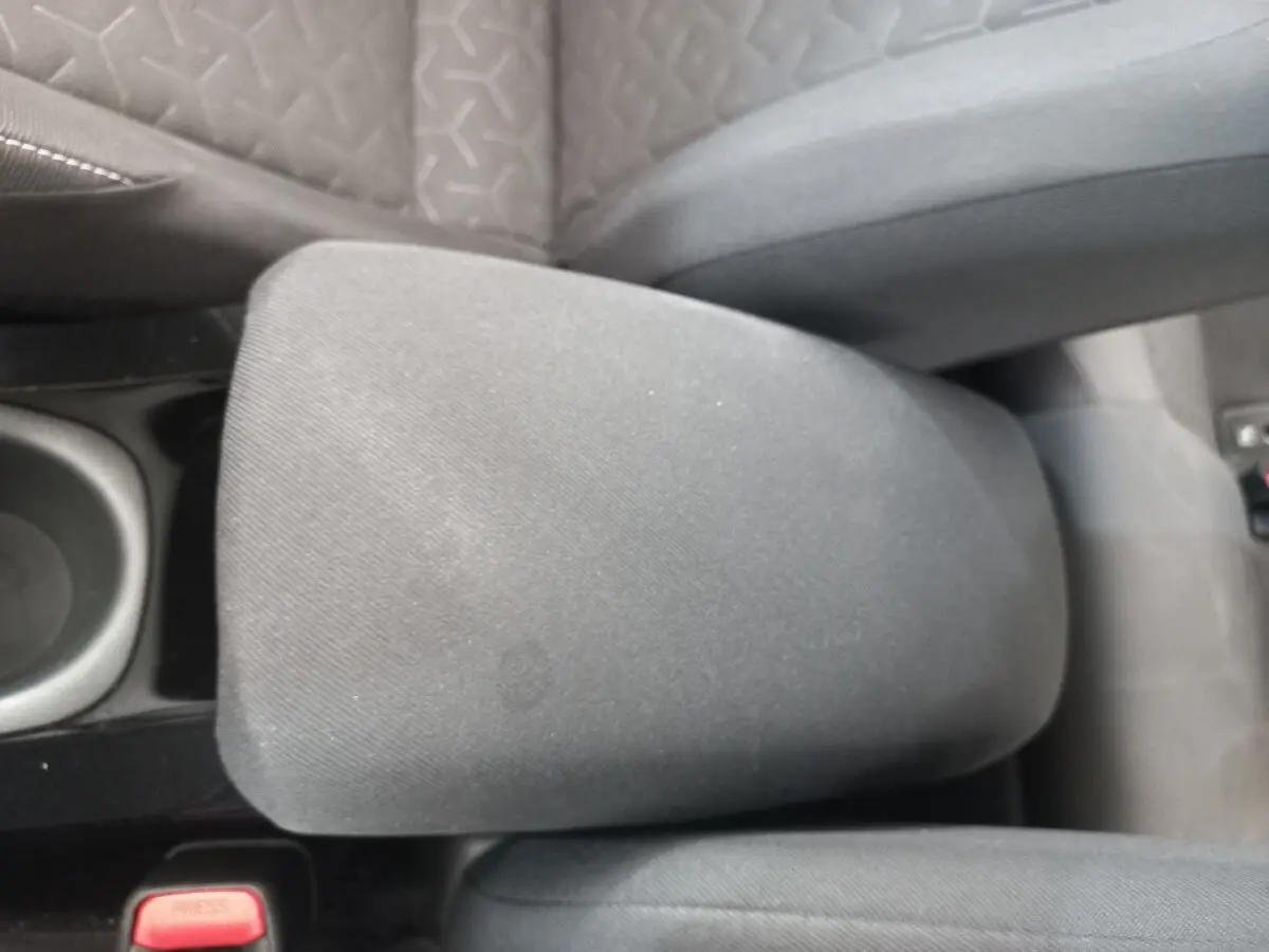 Accoudoir central en tissu gris entre les sièges avant d'une Toyota Corolla hybride 2022, vue de dessus.