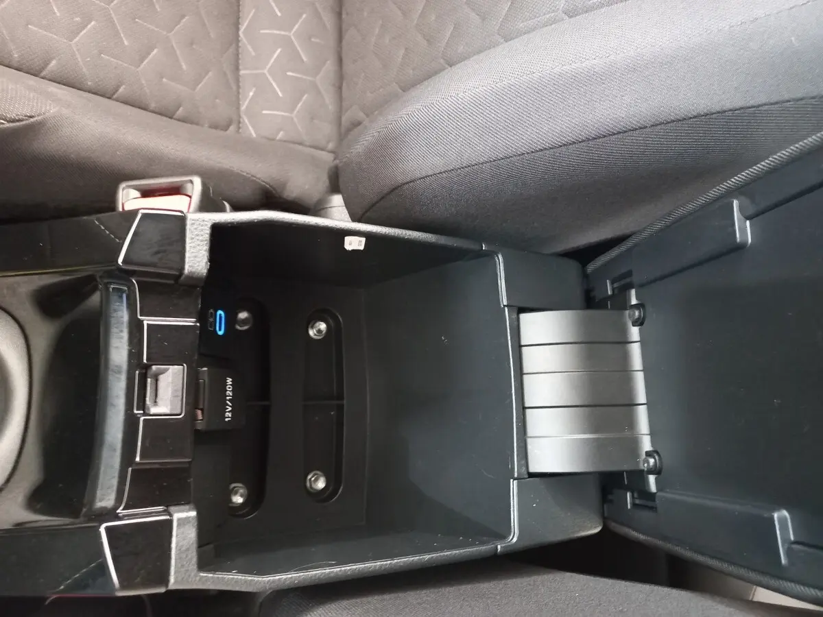 Vue rapprochée de la console centrale ouverte d'une Toyota Corolla hybride 2022, montrant un espace de rangement noir.
