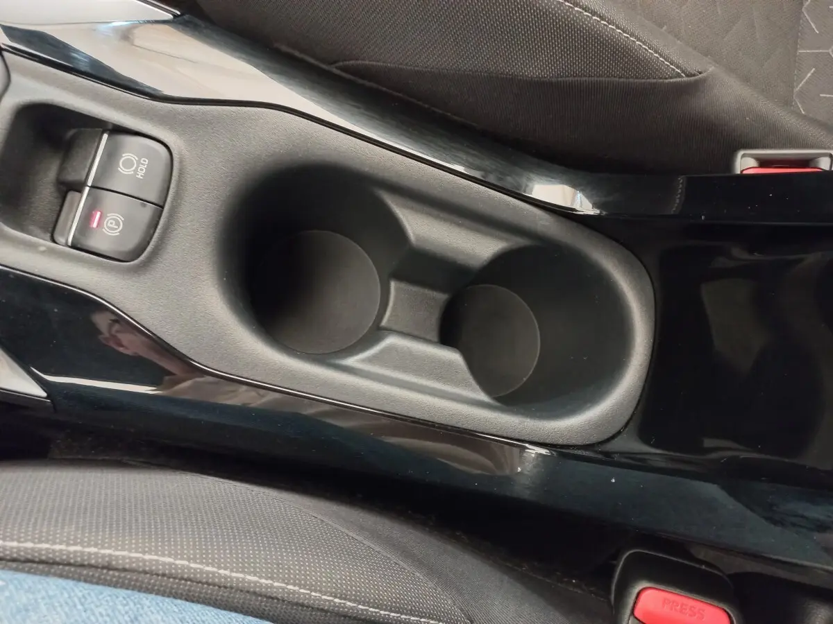 Gros plan sur la console centrale noire avec porte-gobelets et frein à main électrique de la Toyota Corolla hybride 2022.