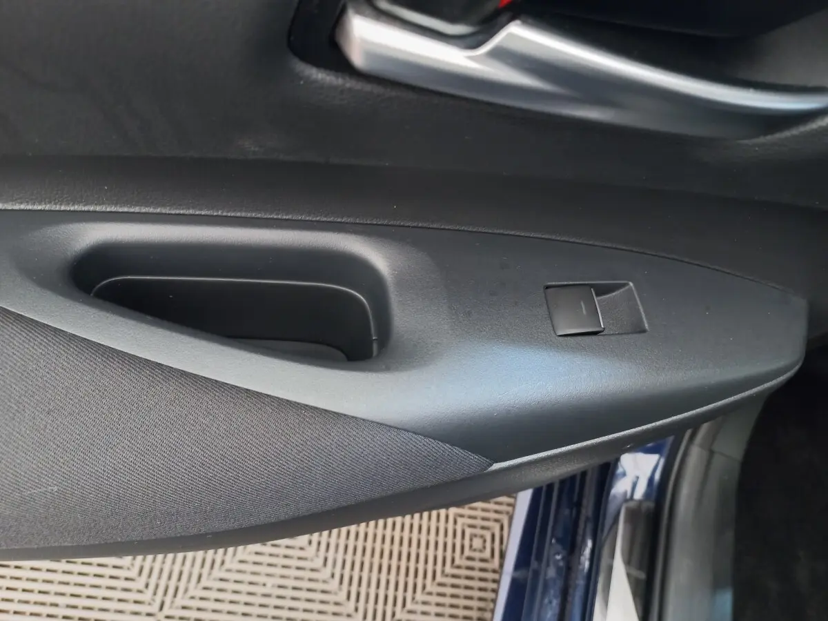 Détail de la porte côté conducteur d'une Toyota Corolla hybride bleu, avec bouton de commande de vitre.